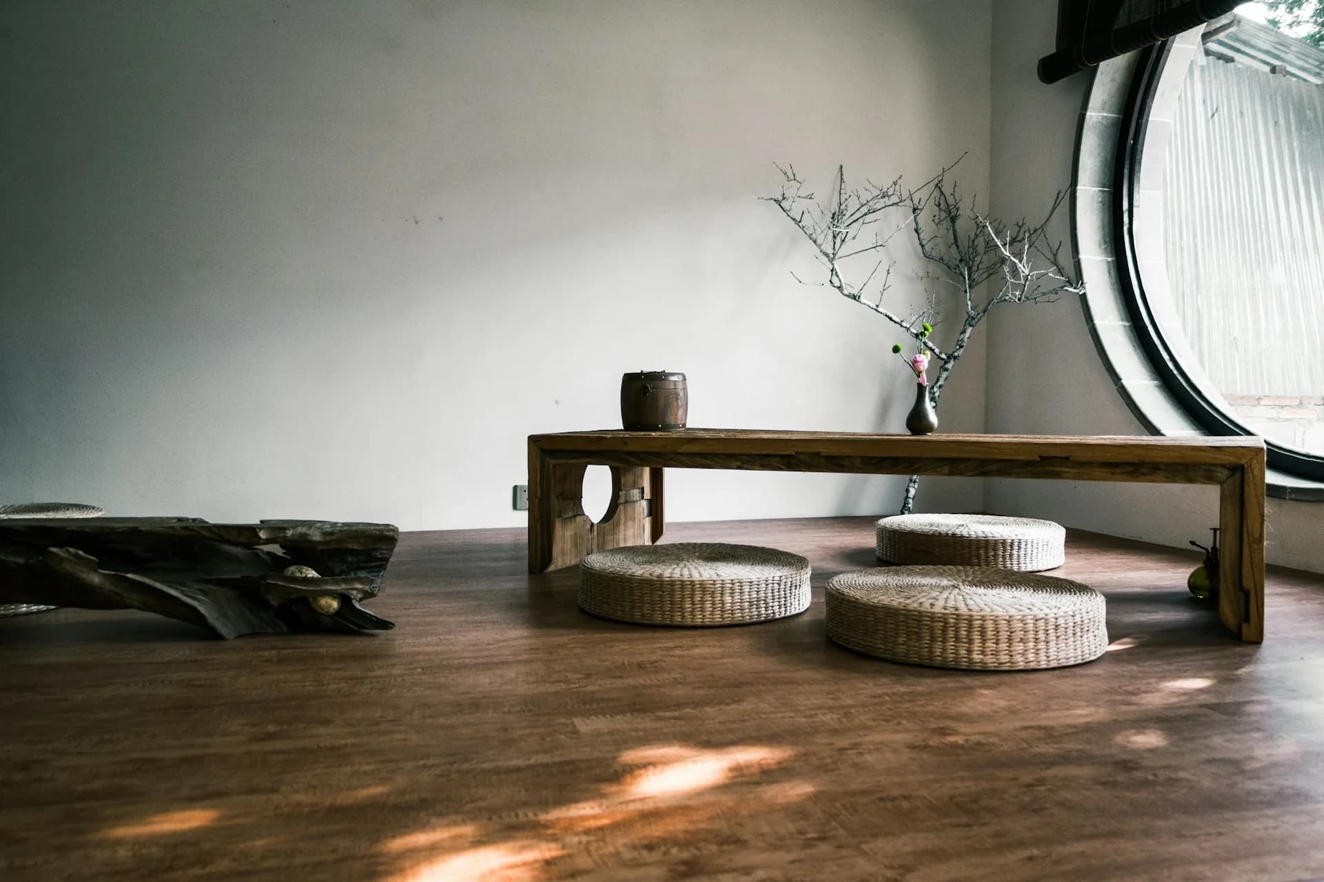Piso de madera iluminado por el sol en una habitación con banca y cojines tejidos