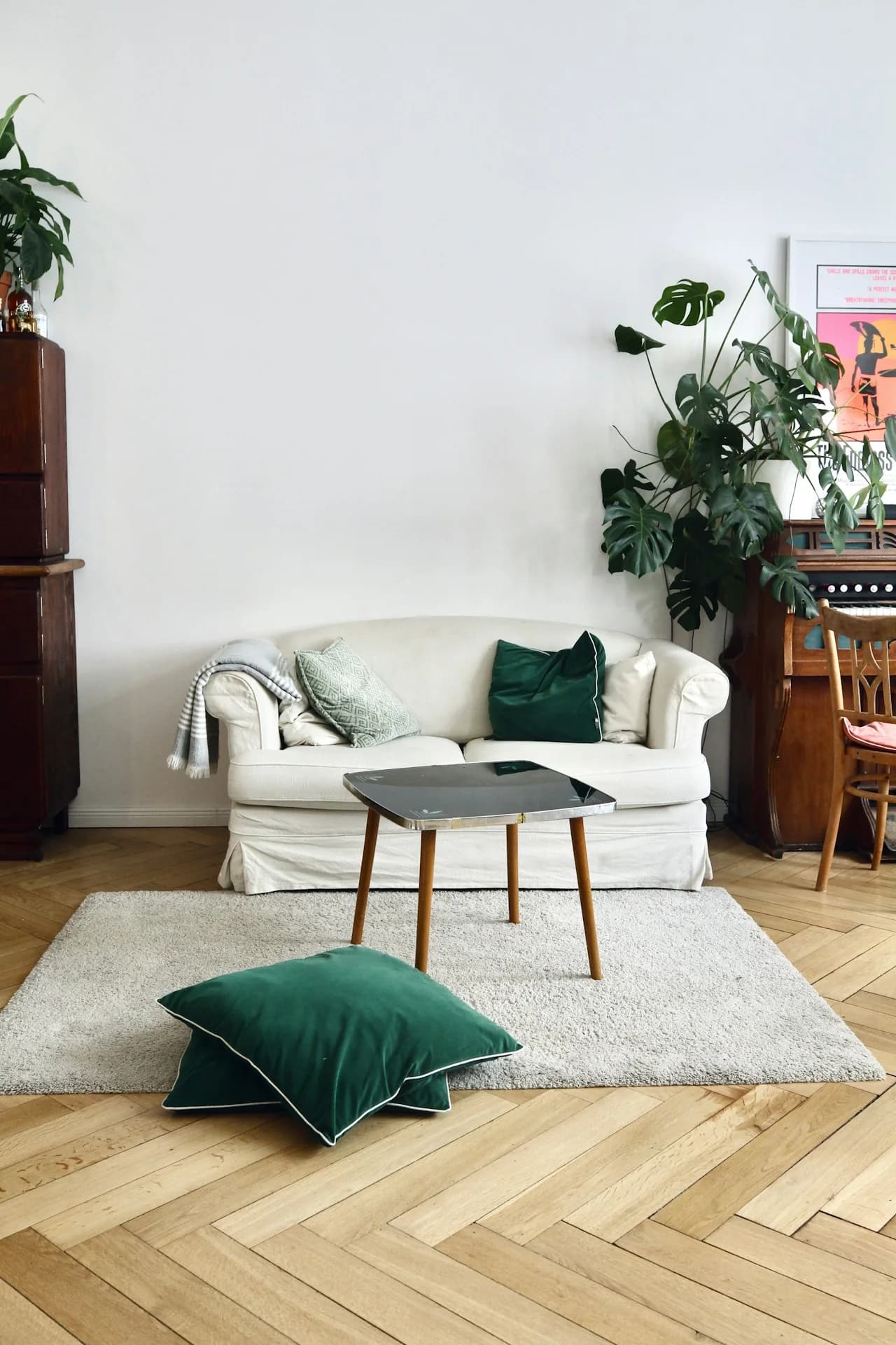 Sofá crema con cojines verdes, mesa de centro y tapete en una sala luminosa